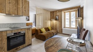 Een moderne keuken met houten kastjes, een ingebouwde oven en een eethoek met een ronde tafel voor vier personen.