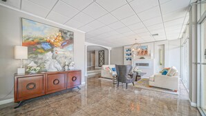 A spacious living area with a large abstract painting, a wooden console, a grey armchair, and a white sofa. - Lakefront Retreat: Updated Condo with Resort Amenities, Lake Views, Pool & Close to Hot Springs Fun! (Hot Springs)