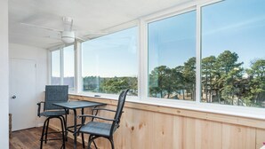 A room with a large window, wooden paneled walls, a ceiling fan, and a table with chairs. - Lakefront Retreat: Updated Condo with Resort Amenities, Lake Views, Pool & Close to Hot Springs Fun! (Hot Springs)