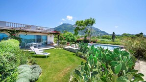 A modern house with a pool, a patio with lounge chairs, and a mountain view. - Sea View exclusive villa with private garden and pool (Forio)