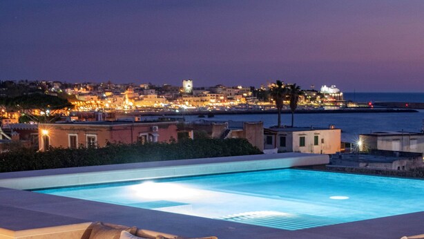 A poolside area with a built-in sofa and a small table, surrounded by a well-maintained lawn. - Sea View exclusive villa with private garden and pool (Forio)