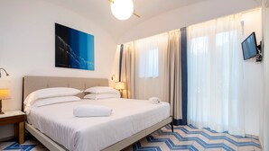 A hotel room with a bed, a nightstand, a lamp, a TV, and a painting on the wall. - Sea View exclusive villa with private garden and pool (Forio)