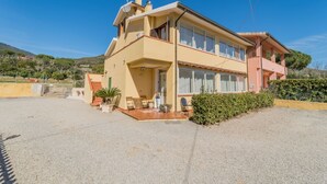 Ein zweistöckiges Haus mit Terrasse, kleinem Garten und Blick auf die umliegende Landschaft.