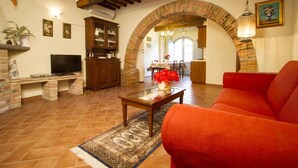 Una sala de estar con un sofá rojo, un televisor, un mueble de madera y una chimenea de ladrillo.