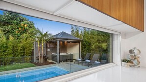 A modern outdoor pool area with a glass balustrade, lounge chairs, and a hot tub. - Bella Beach Resort - An Oasis on the Bellarine (Saint Leonards)