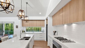 A modern kitchen with white cabinetry, a large island, and a gas stove. - Bella Beach Resort - An Oasis on the Bellarine (Saint Leonards)