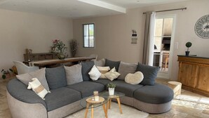 A living room with a grey sectional sofa, a glass coffee table, and a white furry rug.