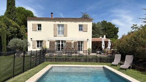 A two-story house with a swimming pool, a fenced patio, and outdoor seating.