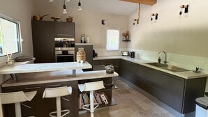 A modern kitchen with a central island, bar stools, and a built-in oven.