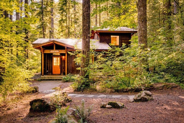 A rustic cabin with a wooden exterior, a front porch, and a visible door.