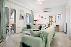 A spacious living area with a sofa set, a dining table, and a kitchen area.