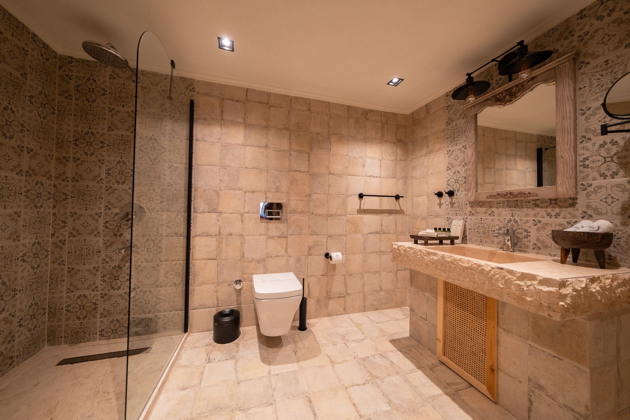 A modern bathroom with a shower, toilet, sink, and a large mirror.