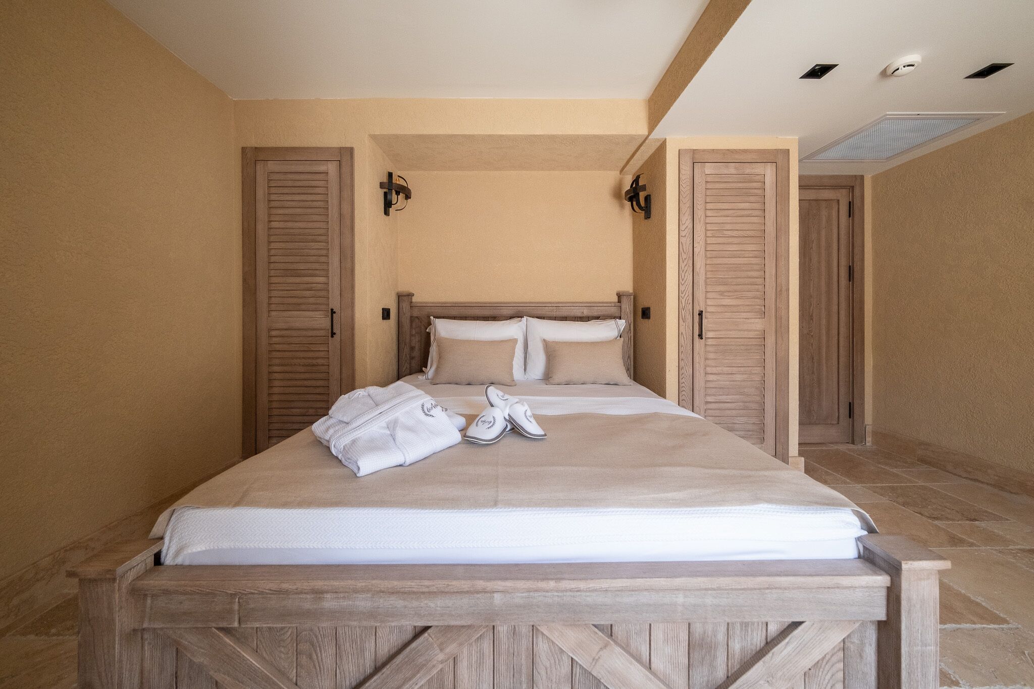 A bedroom with a wooden bed, beige walls, and two doors.
