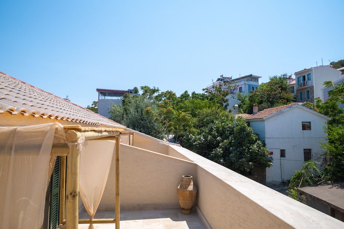 A balcony with a beige tiled floor, a wooden chair, and a large vase.