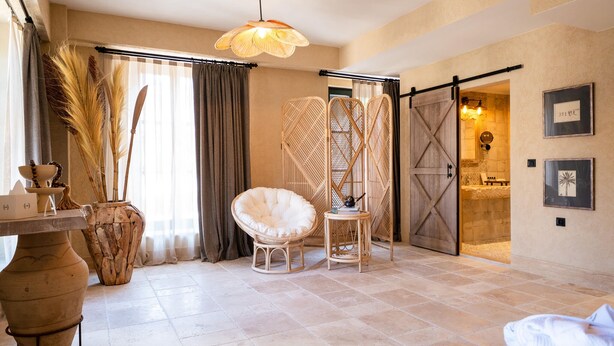 Una habitación con un ventanal grande, una silla, una mesa y una puerta que da a otra estancia.
