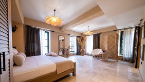 Un dormitorio amplio con una cama grande, dos lámparas colgantes, un espejo y vistas al exterior.
