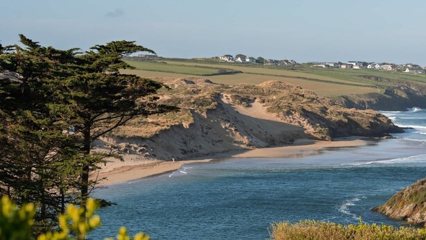 Eine Küstenlandschaft mit Sandstrand, felsiger Küstenlinie und freiem Blick auf den Ozean.