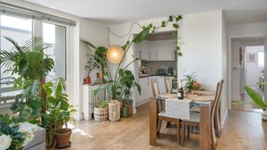 Eine moderne Küche mit Holzschränken, einem Esstisch mit Stühlen und verschiedenen Blumentöpfen.