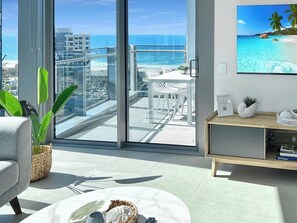 Een moderne woonkamer met een ruim balkon met uitzicht op een strand en de oceaan.