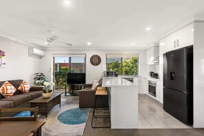 A modern kitchen with a black refrigerator, white cabinets, and a small island.