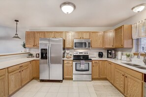 A modern kitchen with wooden cabinets, stainless steel appliances, and a built-in oven. - Lakefront Haven - Families, Golfers, Girl's Trips (Wisconsin Dells)