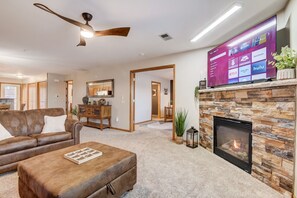 Una sala de estar con chimenea, un sofá, una mesa de centro y un televisor mostrando servicios de streaming.
