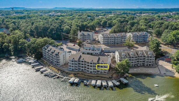 Un hôtel situé au bord de l’eau, composé de plusieurs bâtiments, avec un quai où sont amarrés des bateaux et une vue sur la forêt environnante.