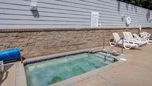 Une petite piscine extérieure avec un mur en pierre et une bâche bleue.