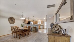 Une cuisine spacieuse avec des meubles de rangement en bois, un coin repas avec une table et des chaises en bois, et un élément décoratif mural.