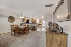 A spacious kitchen with wooden cabinets, a dining area with a wooden table and chairs, and a decorative wall piece.