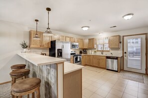 Una cocina moderna con armarios de madera, electrodomésticos de acero inoxidable y una isla de mármol con taburetes de bar.