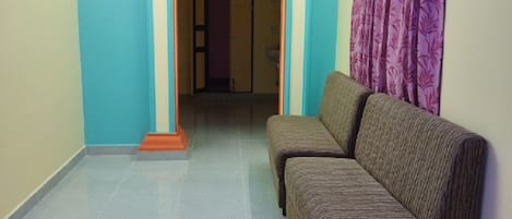 A hallway with a blue wall, a purple curtain, and a sofa.