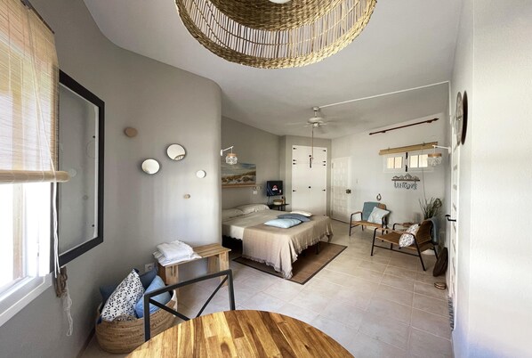 A modern bedroom with a bed, bedside tables, a wooden chair, and a dining table.