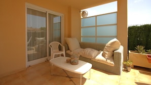 A sunlit patio with a white sofa, a small table, and a white chair. - Golden - Javea, Costa Blanca (Javea)