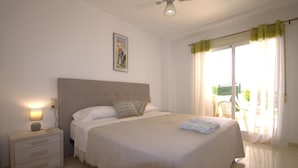 A bedroom with a bed, bedside table, lamp, and a ceiling fan. - Golden - Javea, Costa Blanca (Javea)