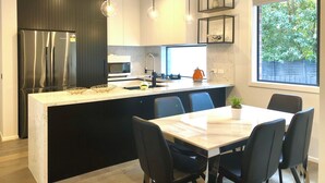 Una cocina moderna con una isla central, armarios negros, electrodomésticos de acero inoxidable e iluminación colgante.