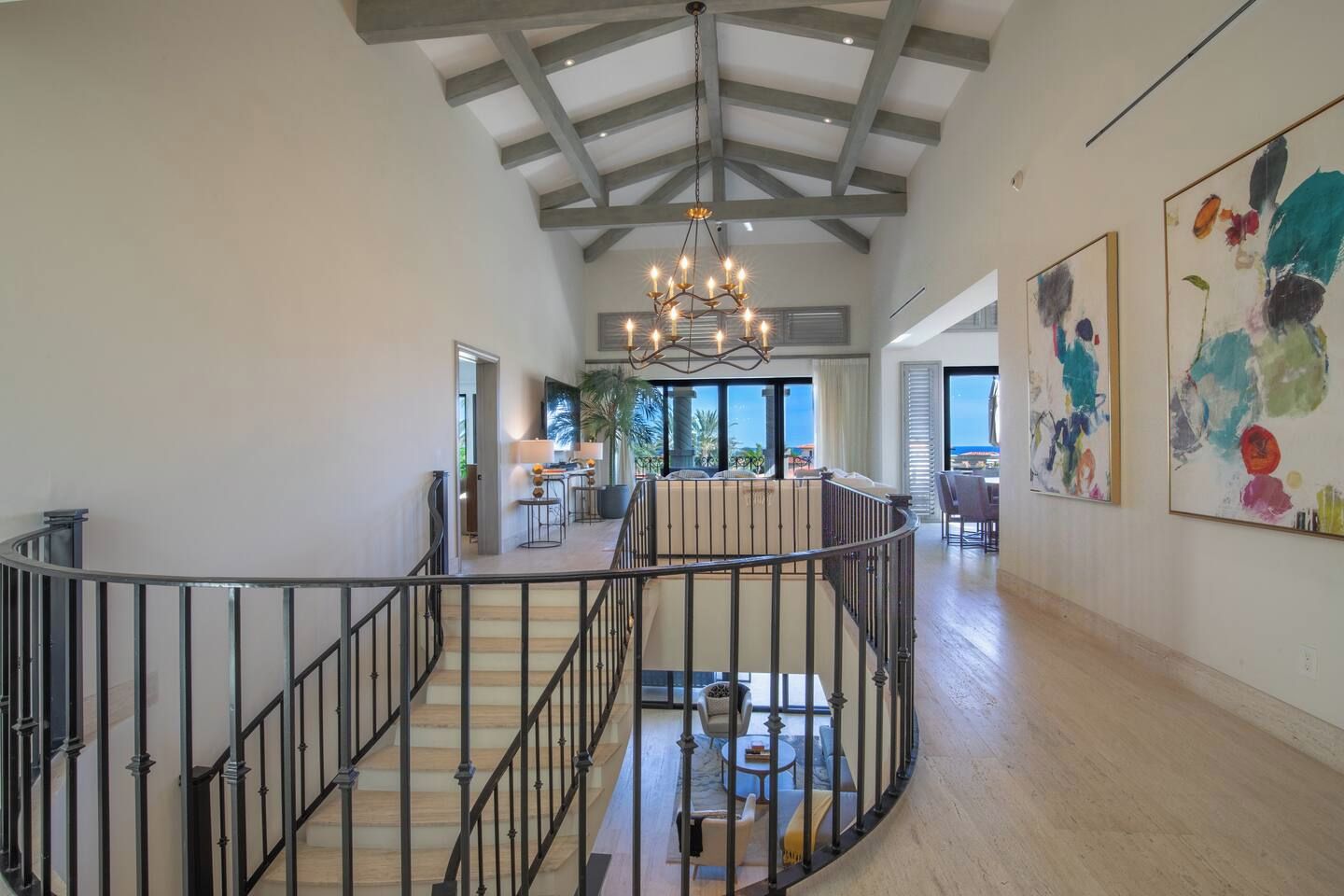 A spacious interior with a curved staircase, a chandelier, and artwork on the walls.