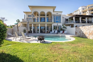 A large house with a swimming pool, outdoor seating, and a stone wall.
