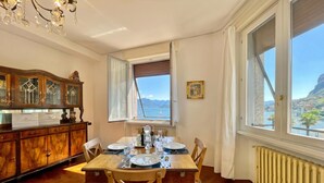 Comedor con una mesa lista para dos personas, un armario de madera y vista al mar a través de una ventana.