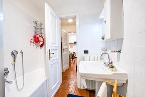 A bathroom with a bathtub, shower, sink, and towel rack.