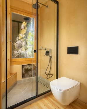 A modern bathroom with a glass shower enclosure, a wooden bench, and a white toilet.