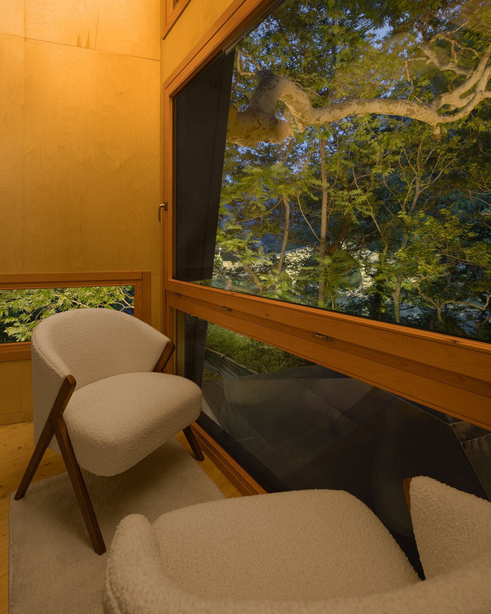 Una habitación con un ventanal grande, una silla y vista a árboles.