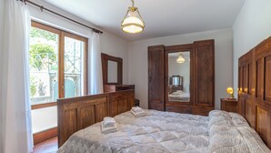 A bedroom with a large bed, wooden wardrobe, and a mirror. - Casa Achille Pianello (Pianello del Lario)