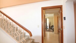 A staircase with a geometric railing leading to a hallway.