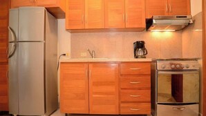 A kitchen with wooden cabinets, a refrigerator, a coffee maker, and an oven.