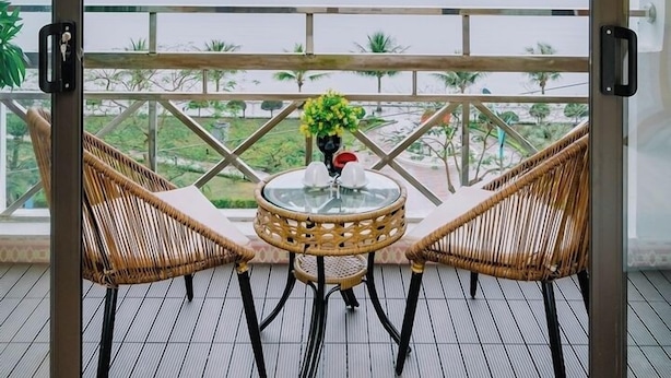 A balcony with wicker chairs and a small table, overlooking a calm sea and distant islands. - Gia Cat Long Hotel (Hai Phong)