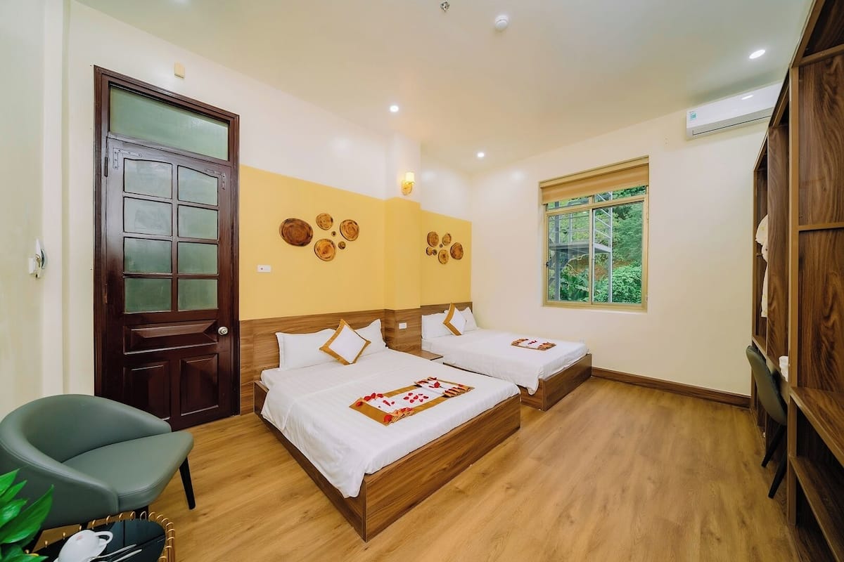 A room with two beds, a wooden door, a window, and a chair.