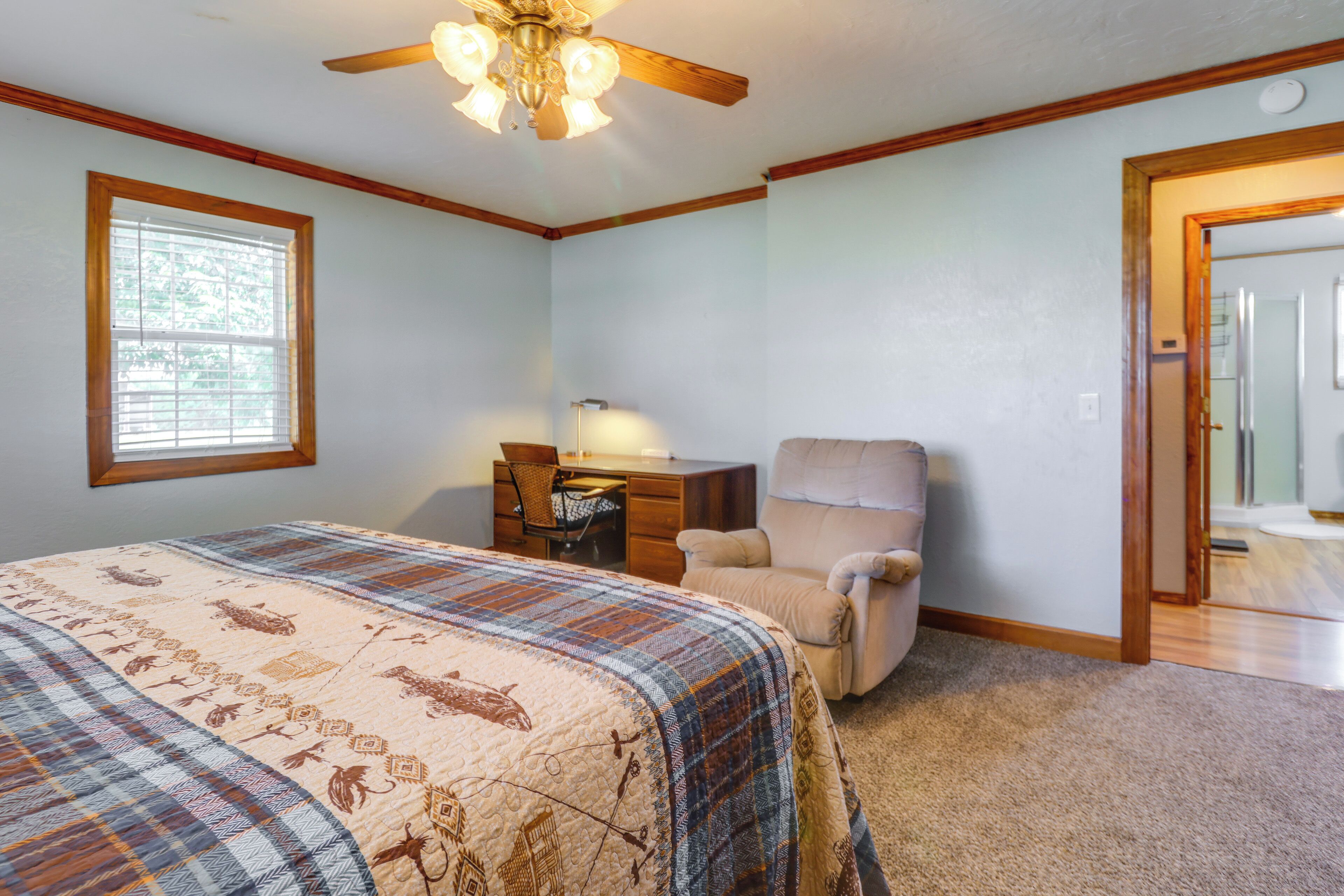 A bedroom with a bed, a desk, a chair, and a ceiling fan.