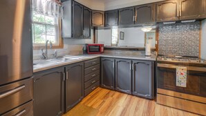 Una cocina con armarios oscuros, electrodomésticos de acero inoxidable, un microondas y un salpicadero de azulejos.