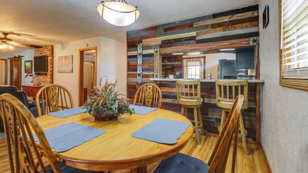Comedor con mesa de madera, sillas y una planta en maceta.
